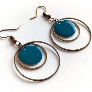 May include: A pair of gold hoop earrings with a teal blue circle in the centre of each hoop.