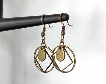 May include: A pair of bronze earrings with a geometric design. Each earring features a circle with a square inside, and a teardrop-shaped pendant hanging from the bottom.