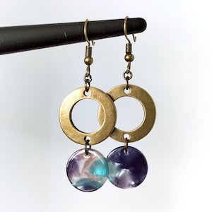 May include: Gold hoop earrings with a dangling round purple and blue iridescent charm.