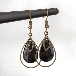 May include: A pair of dangle earrings with black teardrop-shaped glass beads and gold-toned metal accents.