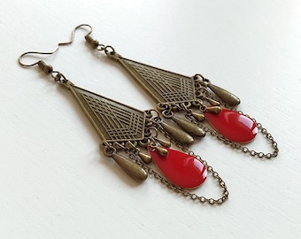May include: A pair of long, dangling earrings with a geometric, triangular design. The earrings are made of bronze metal and feature red enamel teardrop accents.