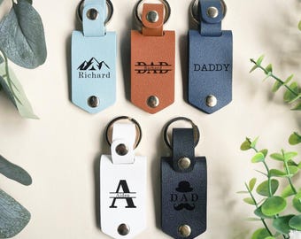 May include: Five leather keychains with different designs and text. The keychains are blue, brown, white, and black. The text on the keychains includes "Richard", "DAD", "DADDY", "Aiden", and "DAD".