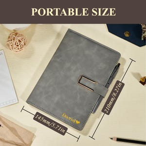 May include: Gray leather-look notebook with a gold-colored clasp and pen holder. The notebook is labeled "David" in gold lettering and measures 5.71 inches wide and 8.27 inches long. The text "PORTABLE SIZE" is at the top.