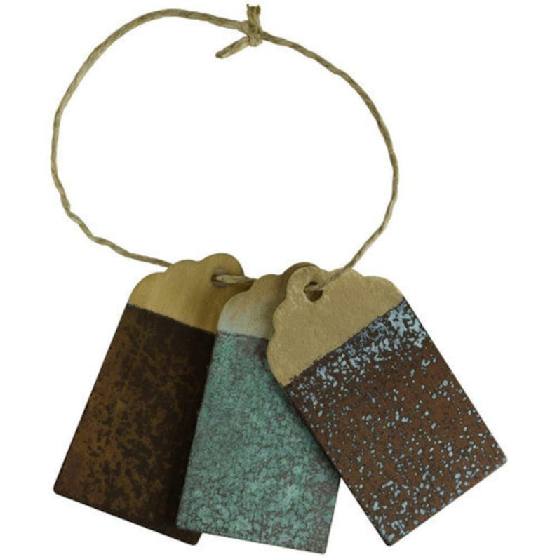 Op de afbeelding: Drie rustieke, rechthoekige, beschilderde houten labels met een touwtje. De labels zijn geschilderd in tinten bruin, teal en blauw met een gespikkelde afwerking.