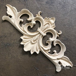 May include: A decorative wooden corner bracket with a carved floral design. The bracket is painted in a light beige colour and has a distressed finish.