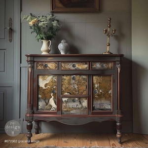 May include: A dark gray cabinet with brown trim and decorative panels featuring a nature scene with birds. The cabinet has drawers and doors, with a distressed finish. The text "#672362 graceful wings" is visible.
