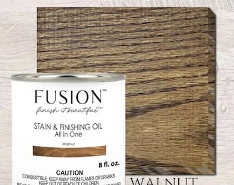 May include: A 8-ounce bottle of Fusion Stain & Finishing Oil in the color Walnut. The bottle is white with black text and a wood grain background. The text on the bottle reads "Fusion finish it beautiful Stain & Finishing Oil All in One Walnut CAUTION COMBUSTIBLE KEEP AWAY FROM FLAMES OR SPARKS. KEEP OUT OF REACH OF CHILDREN. READ CAREFULLY OTHER CAUTIONS ON THE REVERSE PANEL 8 fl. oz."
