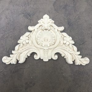 May include: A white, ornate, triangular-shaped decorative moulding with a floral design. The moulding has a central, circular design with a fan-like pattern.