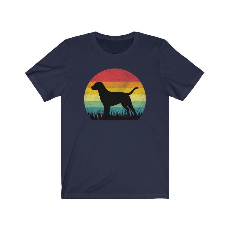 May include: Navy blue t-shirt featuring a silhouette of a dog standing in grass against a retro sunset design. The sunset has bands of red, orange, yellow, and green. A stylish graphic tee for dog lovers.