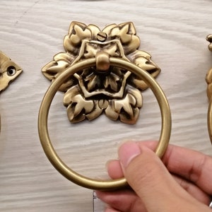 Puede incluir: Un anillo de toalla de metal dorado con un diseño floral decorativo. El anillo está fijado a una pared.