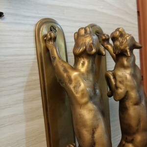 May include: A pair of antique brass door handles shaped like cats. The cats are in a climbing position with their paws raised.