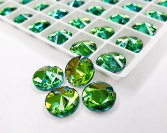 May include: A close-up of six green iridescent glass rhinestones. The rhinestones are round and have a faceted design. They are arranged in a semi-circle on a white surface.