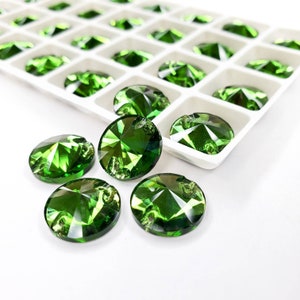 Puede incluir: Primer plano de una bandeja de piedras de cristal redondas verdes. Las piedras de cristal están dispuestas en filas y todas son del mismo tamaño. La bandeja es blanca y tiene un patrón de cuadrícula.