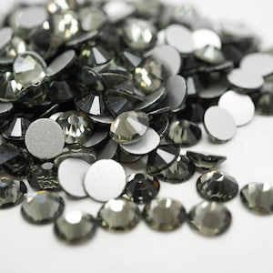 May include: A pile of black rhinestones with a flat back, some with adhesive.
