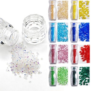 May include: Assortment of 10 small bottles filled with colorful iridescent glass beads. Each bottle has a clear lid and a clear base. The beads are in various colors, including gold, yellow, blue, pink, red, and green.