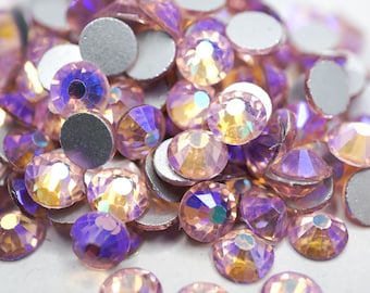 May include: A pile of iridescent pink and purple rhinestones with a silver backing.