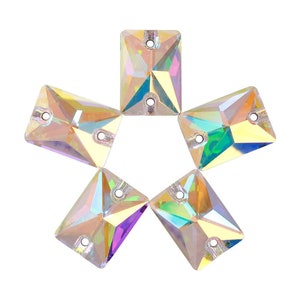 Puede incluir: Seis piedras de imitación rectangulares iridiscentes para coser con dos agujeros cada una. Las piedras de imitación están dispuestas en forma de estrella.