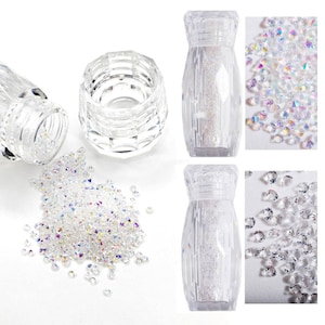 Puede incluir: Un frasco de vidrio transparente lleno de diamantes de imitación transparentes iridiscentes. El frasco tiene una superficie texturizada y una tapa. Los diamantes de imitación están esparcidos alrededor del frasco.