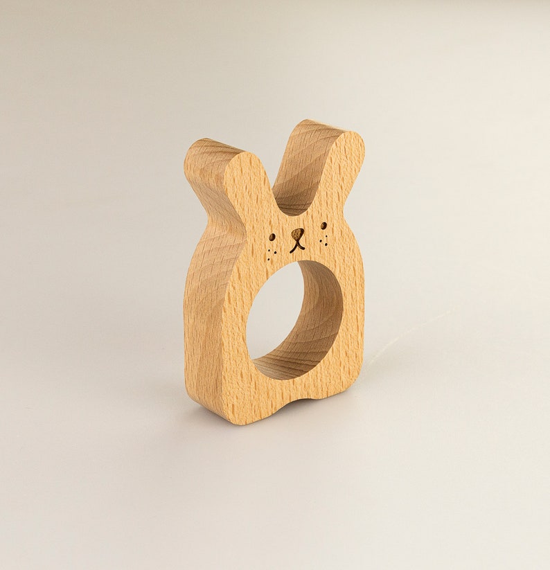 May include: Wooden bunny napkin ring with a carved face and a hole in the center for holding napkins.