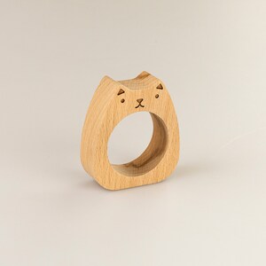 May include: Wooden napkin ring shaped like a cat with a simple face design.