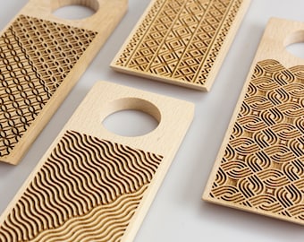 May include: Four wooden bottle stoppers with different geometric patterns. Each stopper has a circular cutout for the bottle neck.