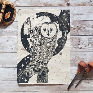 May include: Black and white linocut print of an owl perched on a branch with a crescent moon and stars in the background.