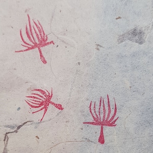 May include: Three red stylized plant designs on a white background. The designs are simple and abstract, with a central stem and radiating lines.