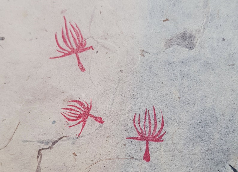 May include: Three red stylized plant designs on a white background. The designs are simple and abstract, with a central stem and radiating lines.