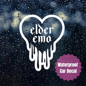 May include: A white heart-shaped car decal featuring the text "elder emo" in a gothic font, with the bottom of the heart design appearing to drip downwards. A purple starburst-shaped badge in the corner displays the text "Waterproof Car Decal".