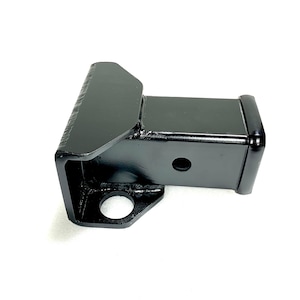 May include: A black trailer hitch receiver, a square tube with a mounting plate and a hole for a pin. The hitch is made of steel and has a glossy finish. The receiver is designed to fit into a vehicle's trailer hitch.