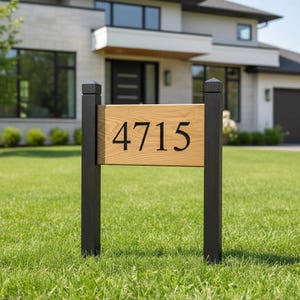 May include: A wooden address sign with the number "4715" in black lettering. The sign is mounted on two black posts and set in a green lawn. A modern house is in the background.
