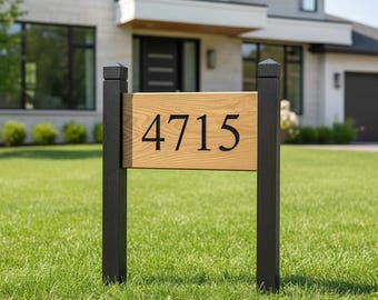 May include: A wooden address sign with the number "4715" in black lettering. The sign is mounted on two black posts and set in a green lawn. A modern house is in the background.