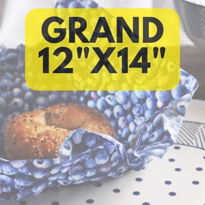 May include: A blue and white patterned reusable food wrap with a bagel inside. The wrap is labeled "GRAND 12" X 14"".