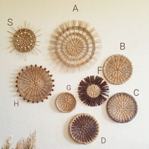 May include: A collection of eight round woven wall decorations in various sizes and styles. The pieces are made from natural materials and have a rustic, bohemian aesthetic.