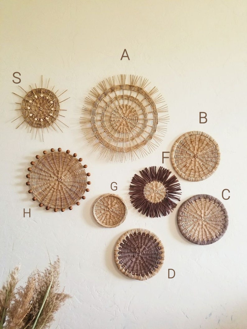 May include: A collection of eight round woven wall decorations in various sizes and styles. The pieces are made from natural materials and have a rustic, bohemian aesthetic.