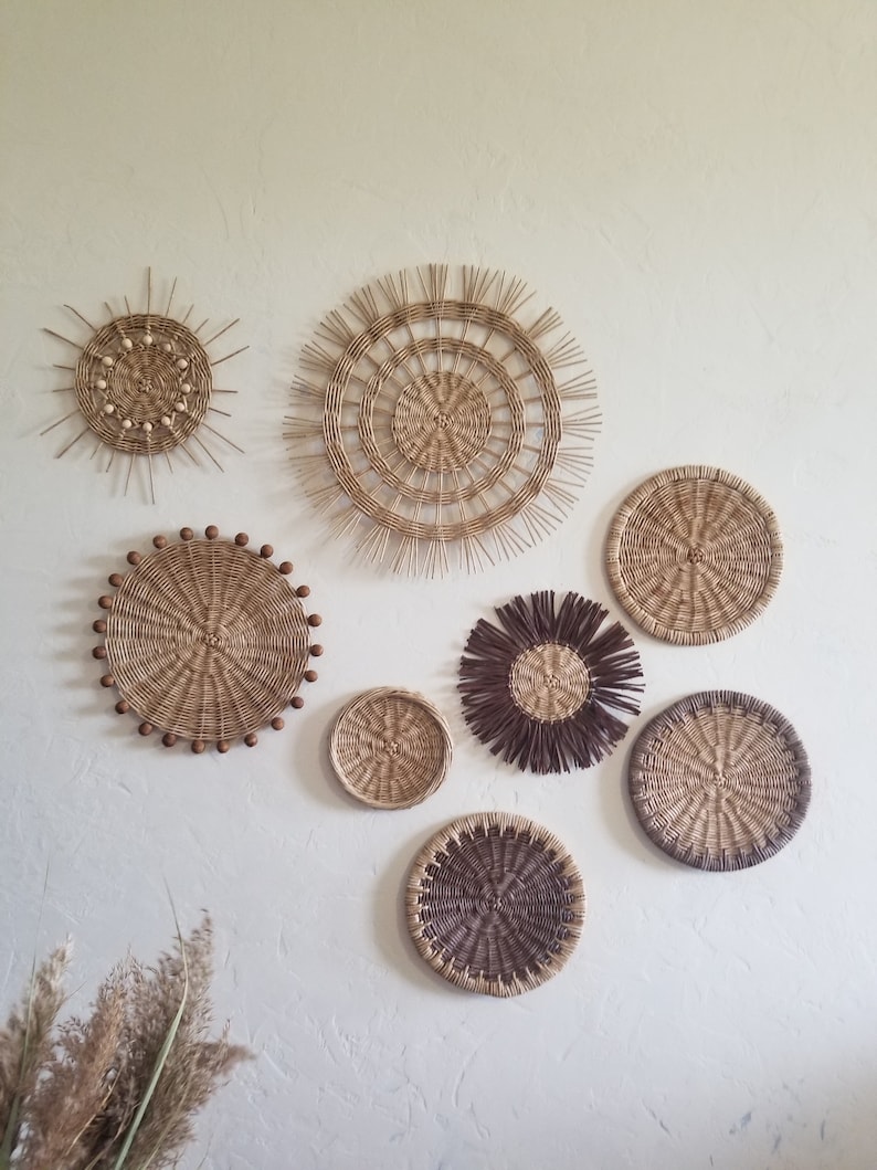 May include: A collection of seven round woven wall decorations in various sizes and patterns. The pieces are made from natural materials and have a rustic, bohemian aesthetic.