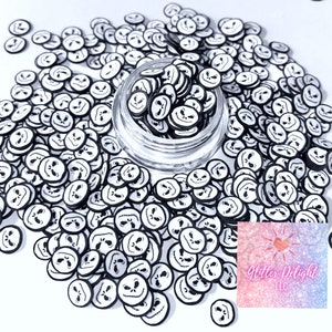 May include: A clear glass jar filled with black and white Jack Skellington face shaped confetti. The confetti is scattered around the jar on a white surface. The text "Glitter Delight LLC" is visible in the lower right corner of the image.