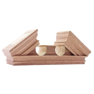 Può includere: Un pezzo di modanatura architettonica in legno marrone caratterizzato da una base orizzontale con un profilo decorativo e due sezioni laterali angolate. La sezione centrale contiene due ritagli circolari che rivelano la venatura del legno chiaro.
