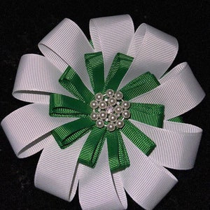 May include: A white and green ribbon bow with a pearl and rhinestone embellishment in the center.
