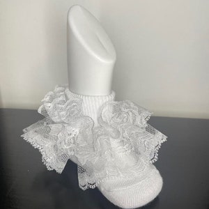 May include: White ankle socks with a white lace ruffle trim. The socks are on a white mannequin.