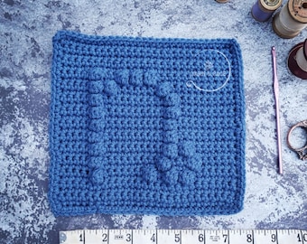 May include: A blue crocheted square with a textured design. The square is 7 inches wide and 7 inches long.