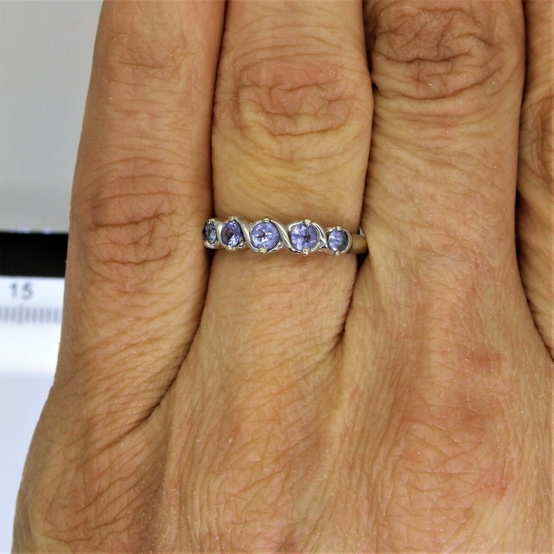 May include: A silver band ring with five purple gemstones set in a wavy pattern.