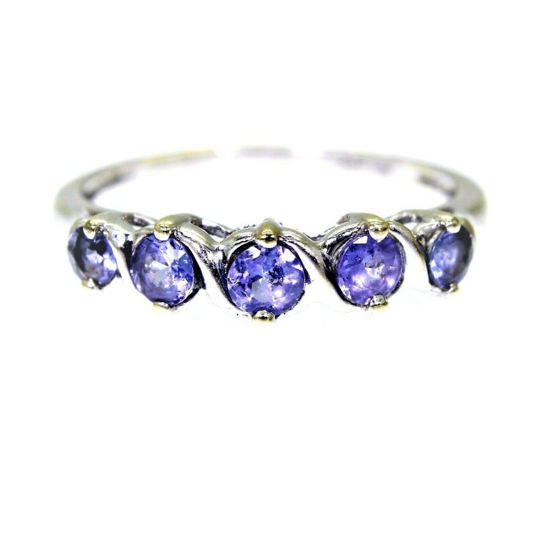 May include: A silver band ring with five round purple gemstones set in a wavy design. The gemstones are accented with gold.