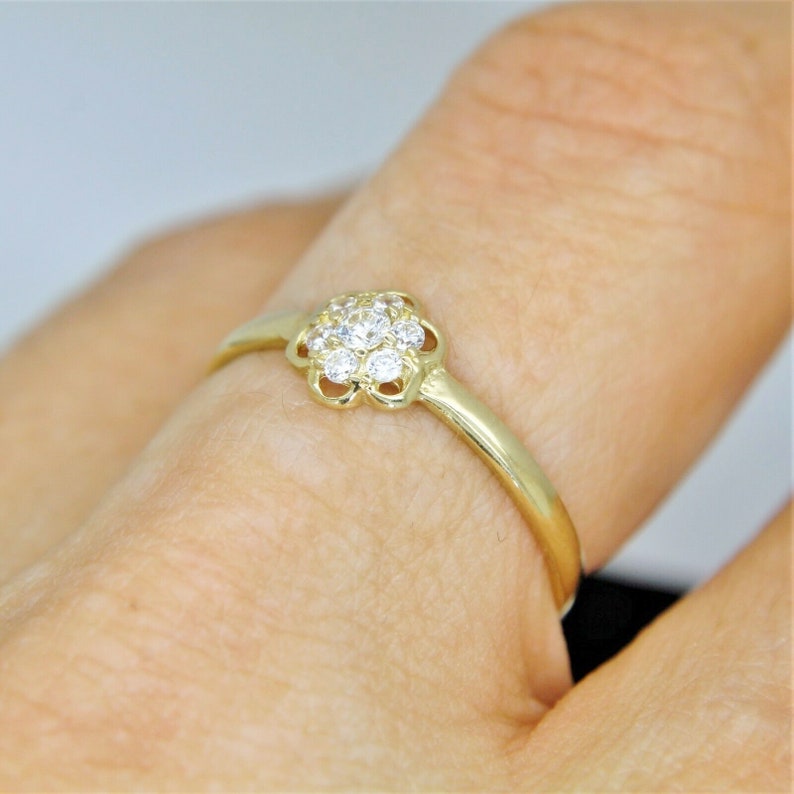 May include: A gold ring with a cluster of small diamonds set in a flower-shaped design.