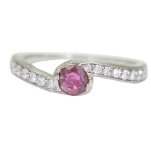 Può includere: Un anello d'argento con una vibrante gemma rosa al centro. La fascia è adornata da piccole pietre bianche scintillanti. Questo elegante gioiello è perfetto per aggiungere un tocco di raffinatezza a qualsiasi outfit.