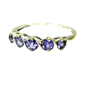 May include: A silver ring with five purple gemstones set in a twisted band.