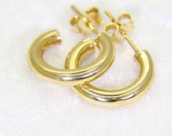 May include: A pair of gold-colored hoop earrings. The earrings are a classic, minimalist design, featuring a smooth, polished surface. The earrings are small and lightweight, perfect for everyday wear.