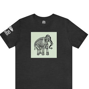 Puede incluir: Una camiseta gris oscuro jaspeada con un esqueleto de elefante impreso en la parte delantera. El elefante está en un cuadro verde claro.