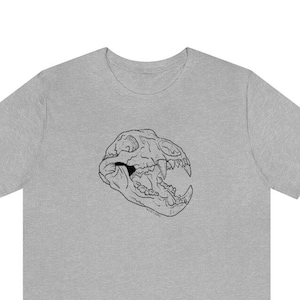Puede incluir: Una camiseta gris jaspeada con un dibujo de línea negra de una calavera de animal.