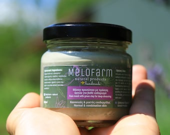 Può includere: Un piccolo barattolo di vetro con un coperchio nero che contiene una maschera per il viso in argilla verde. Il barattolo ha un'etichetta con il testo "MeLoFarm natural products handmade" e "Μάσκα προσώπου με πράσινη άργιλο για βαθύ καθαρισμό" in greco. L'etichetta indica anche "Face mask with green clay for deep cleansing" e "Κανονικές & μικτές επιδερμίδες" in greco. L'etichetta indica anche "Normal & combination skin".